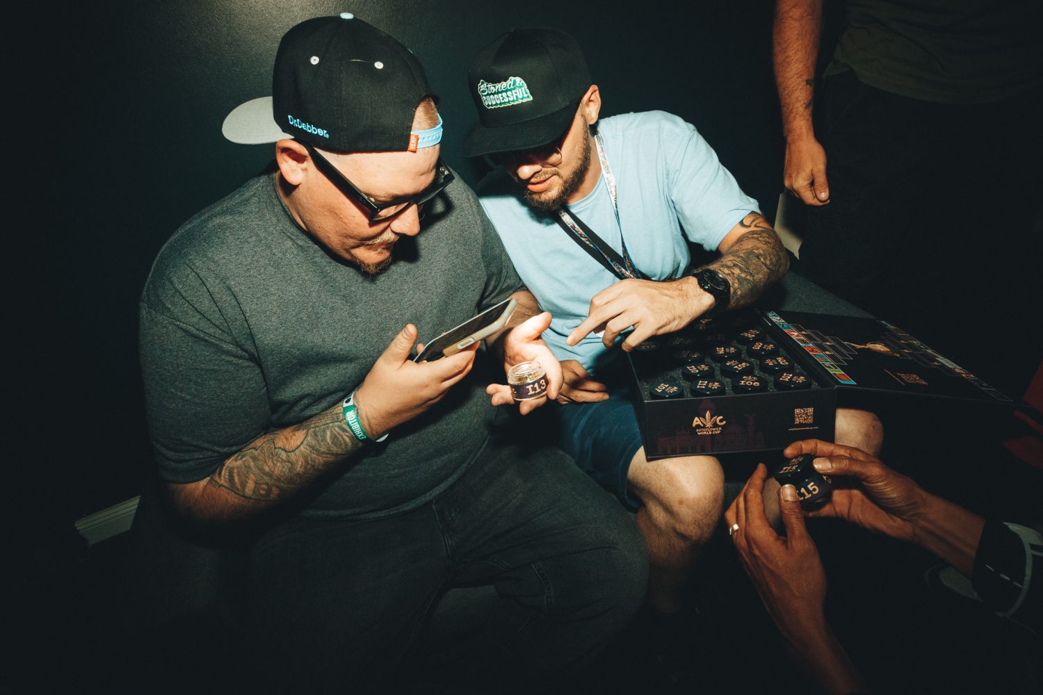 wo attendees inspecting a coded, blind-judging sample jar (I13) from the official Autoflower World Cup 2026 judging kit in Berlin.