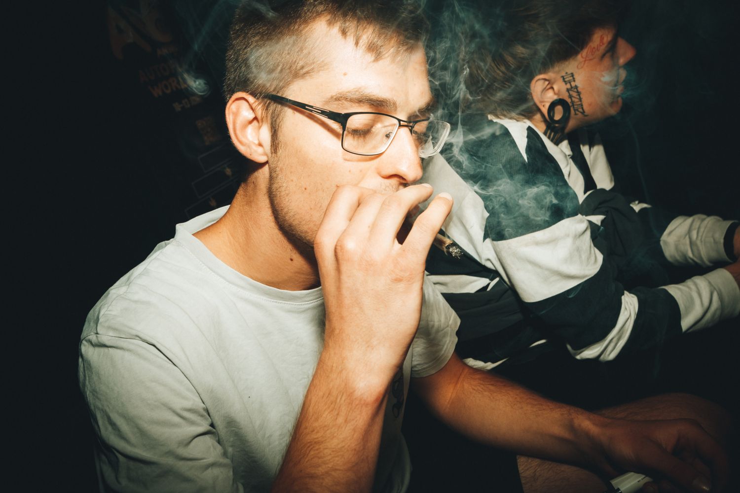 Attendee in glasses smoking a joint amid drifting smoke at the Autoflower World Cup 2026 in Berlin