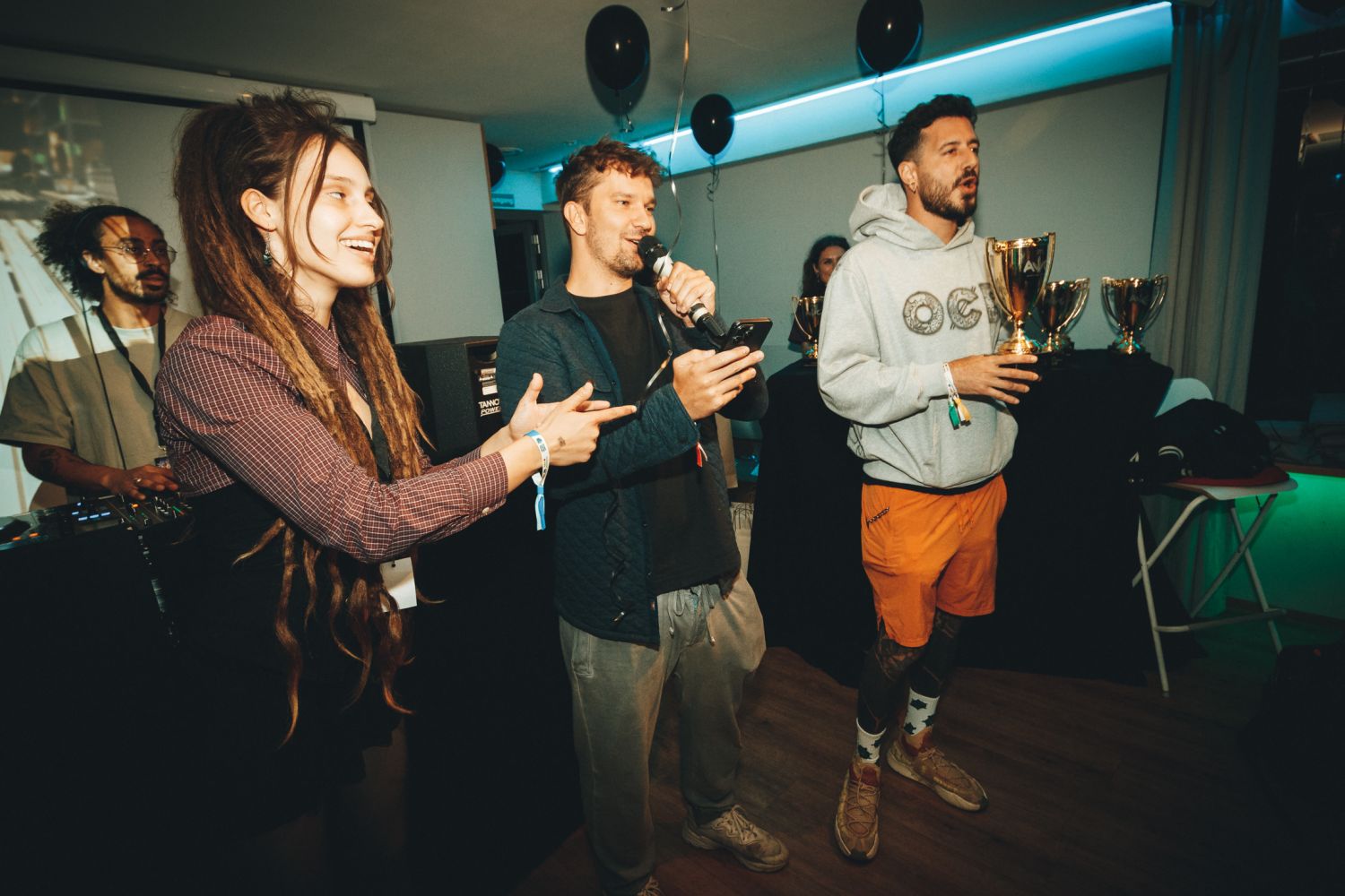 Hosts announcing winners on stage at the Autoflower World Cup awards ceremony, with gold trophies and black balloons in the background